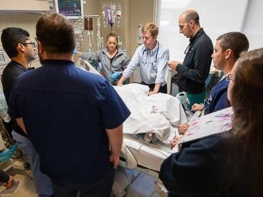Medical team circles the bed of a hospitalized patient